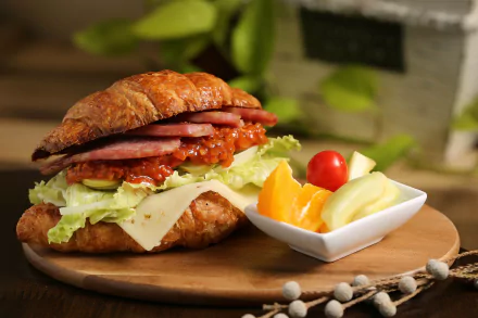 A delectable sandwich made with layers of ham, sauce, lettuce, and cheese, presented on a wooden board alongside a dish of fresh fruit, serving as an appealing HD PC desktop wallpaper.