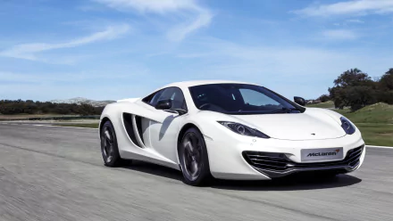 White McLaren MP4-12C supercar speeding on an open road under a blue sky, captured in a high-definition desktop wallpaper background.