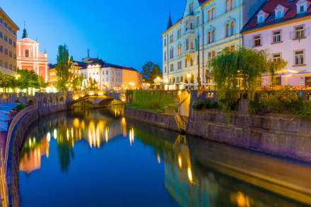 2K Quad HD PC desktop wallpaper and background: nighttime view of illuminated, man-made town buildings and bridges reflecting on the Ljubljanica canal and river in Ljubljana, Slovenia.