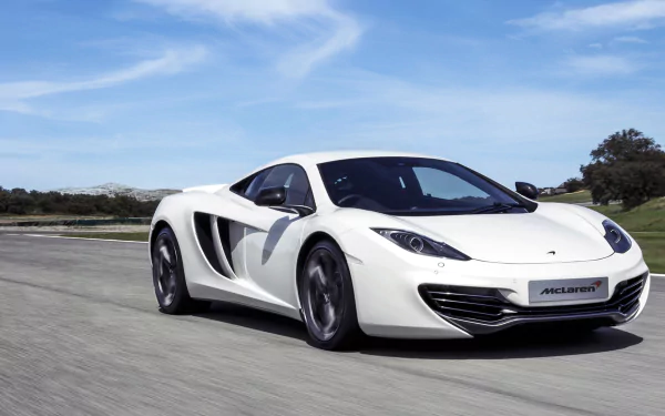 White McLaren MP4-12C supercar speeding on an open road under a blue sky, captured in a high-definition desktop wallpaper background.