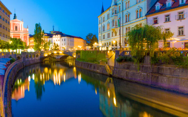 2K Quad HD PC desktop wallpaper and background: nighttime view of illuminated, man-made town buildings and bridges reflecting on the Ljubljanica canal and river in Ljubljana, Slovenia.