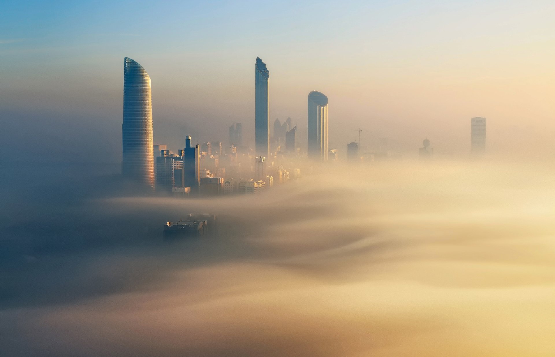 A foggy Dubai skyline with modern skyscrapers rising above thick mist, showcasing the city's iconic man-made architecture in the United Arab Emirates.
