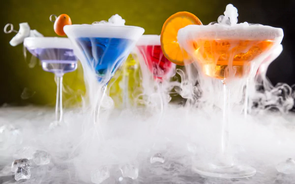 Vibrant cocktails in glassware emit swirling smoke against a contrasting backdrop, creating a striking 4K Ultra HD desktop wallpaper of drinks and food artistry.
