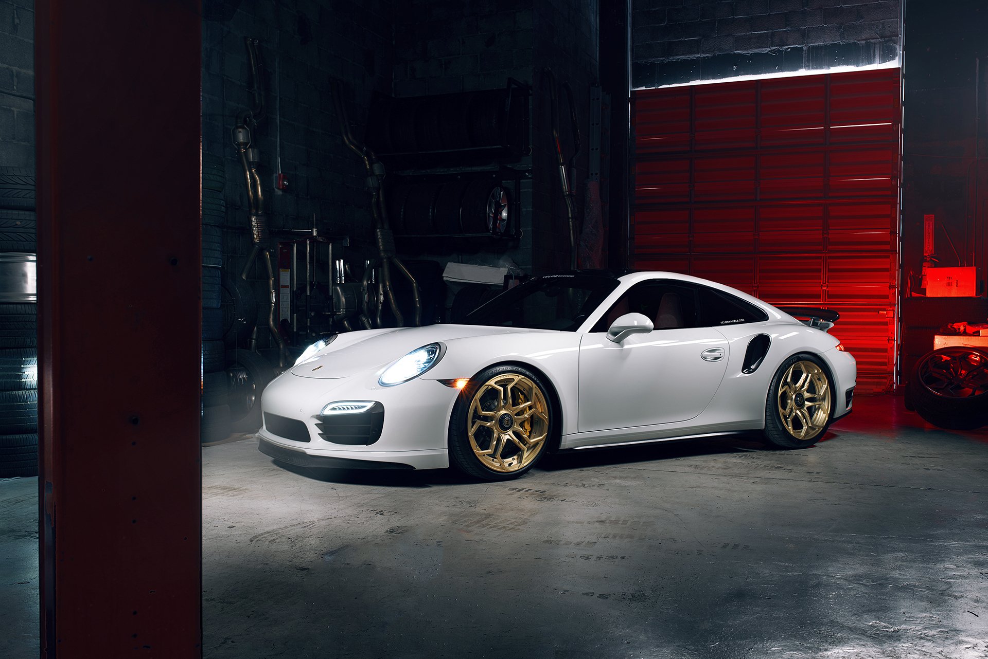 White Porsche 911 Turbo with gold rims parked inside a dimly lit garage, captured in a high-definition desktop wallpaper style.