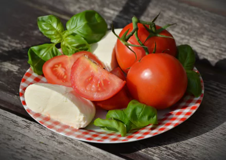 A 4K Ultra HD image of fresh tomatoes, mozzarella cheese, and basil leaves arranged on a checkered plate, highlighting vibrant fruit and cheese.