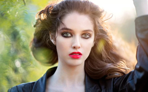 Close-up of a brunette model with hazel eyes and red lipstick, set against a soft bokeh background, captured in stunning 8K Ultra HD quality.