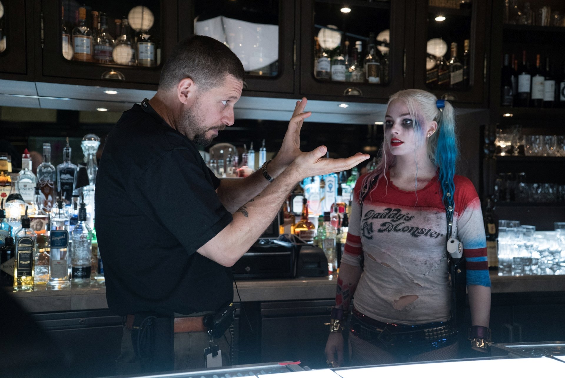 Harley Quinn, portrayed by Margot Robbie, engages in a lively exchange at a bar in this dramatic scene from Suicide Squad, captured in stunning 4K Ultra HD quality.