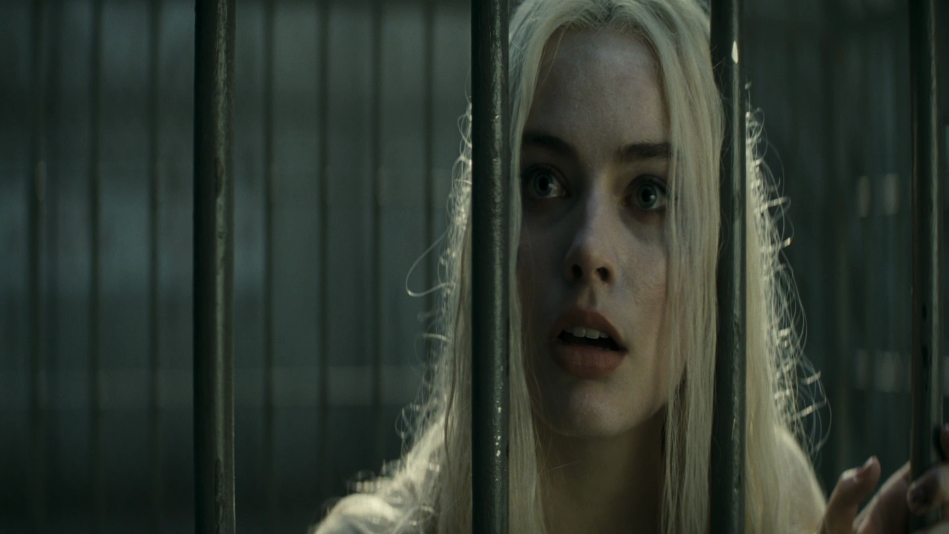 Harley Quinn, portrayed by Margot Robbie in *Suicide Squad*, gazes through bars in this striking HD wallpaper, capturing her intense and iconic character moment.
