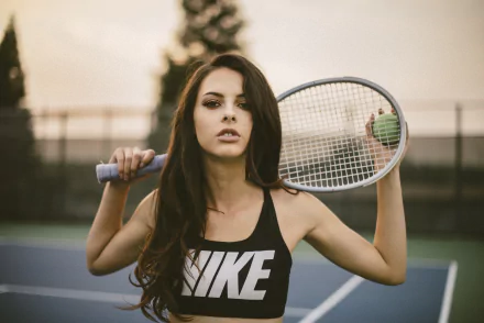 Brunette woman model with brown eyes poses confidently on a tennis court, holding a racket behind her shoulders in a 4K Ultra HD desktop wallpaper.