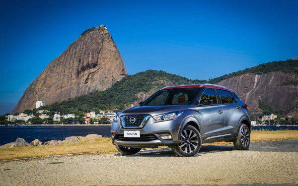 Silver Nissan Kicks SUV parked on a coastal road with Sugarloaf Mountain behind — Nissan vehicle in 4K Ultra HD PC desktop wallpaper.