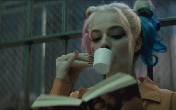 HD wallpaper featuring Margot Robbie as Harley Quinn in the movie Suicide Squad, sipping from a cup and reading a book in a prison cell.