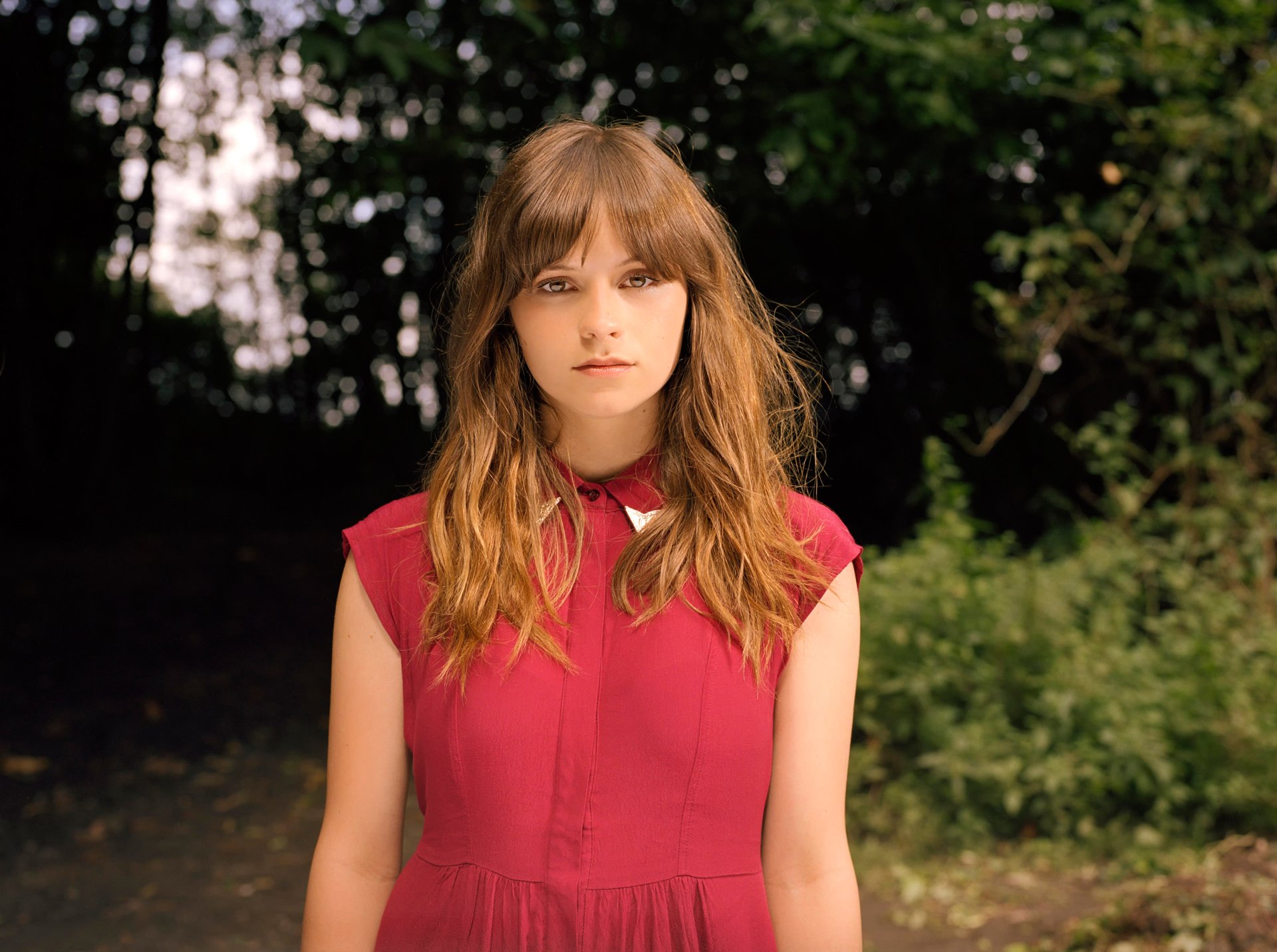 Gabrielle Aplin, English singer and brunette, poses outdoors wearing a red dress in this 4K Ultra HD PC desktop wallpaper and background.