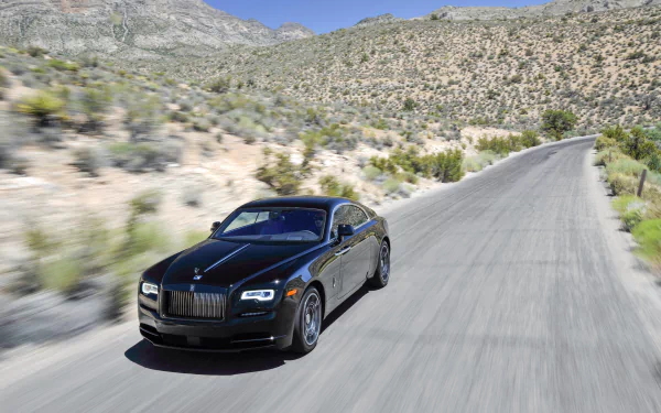 Black Rolls-Royce Wraith driving on a winding mountain road under clear blue sky, captured in sharp 4K Ultra HD detail.