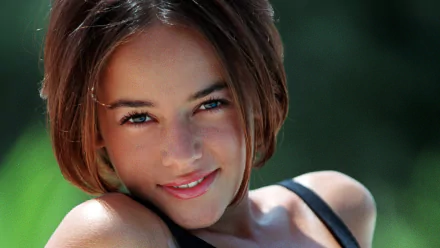 HD PC desktop wallpaper featuring a close-up of Alizée smiling softly against a blurred green background, capturing a serene and musical vibe.