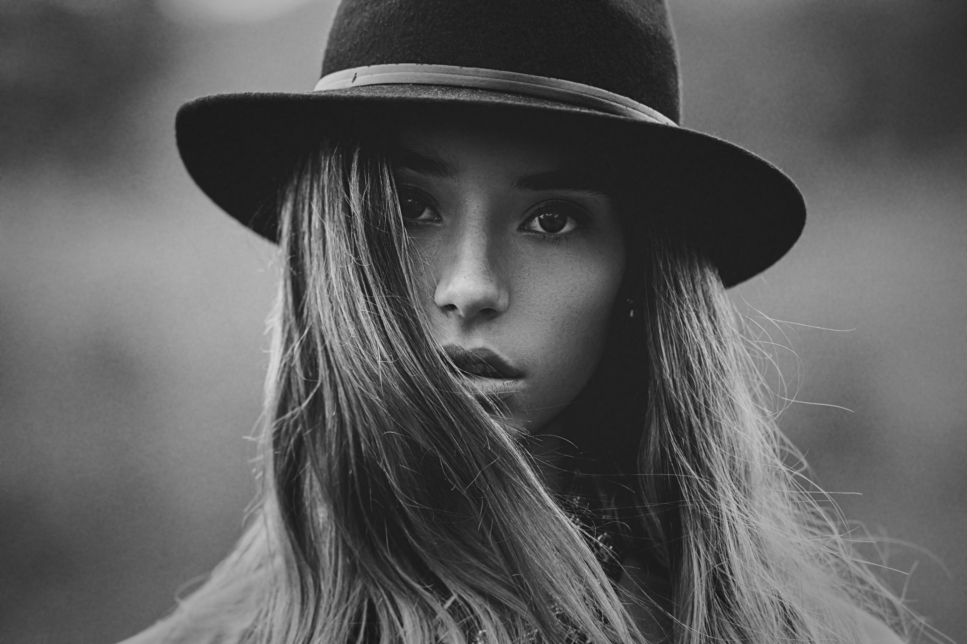 Black and white 4K Ultra HD wallpaper featuring a close-up of a woman's face partially covered by long hair and a wide-brimmed hat.