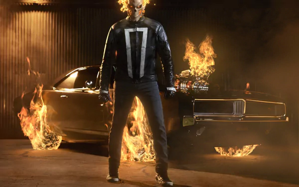 Robbie Reyes as Ghost Rider stands confidently in front of a fiery backdrop, featuring his iconic vehicle, from Marvel's Agents of S.H.I.E.L.D. This HD wallpaper showcases his intense presence.
