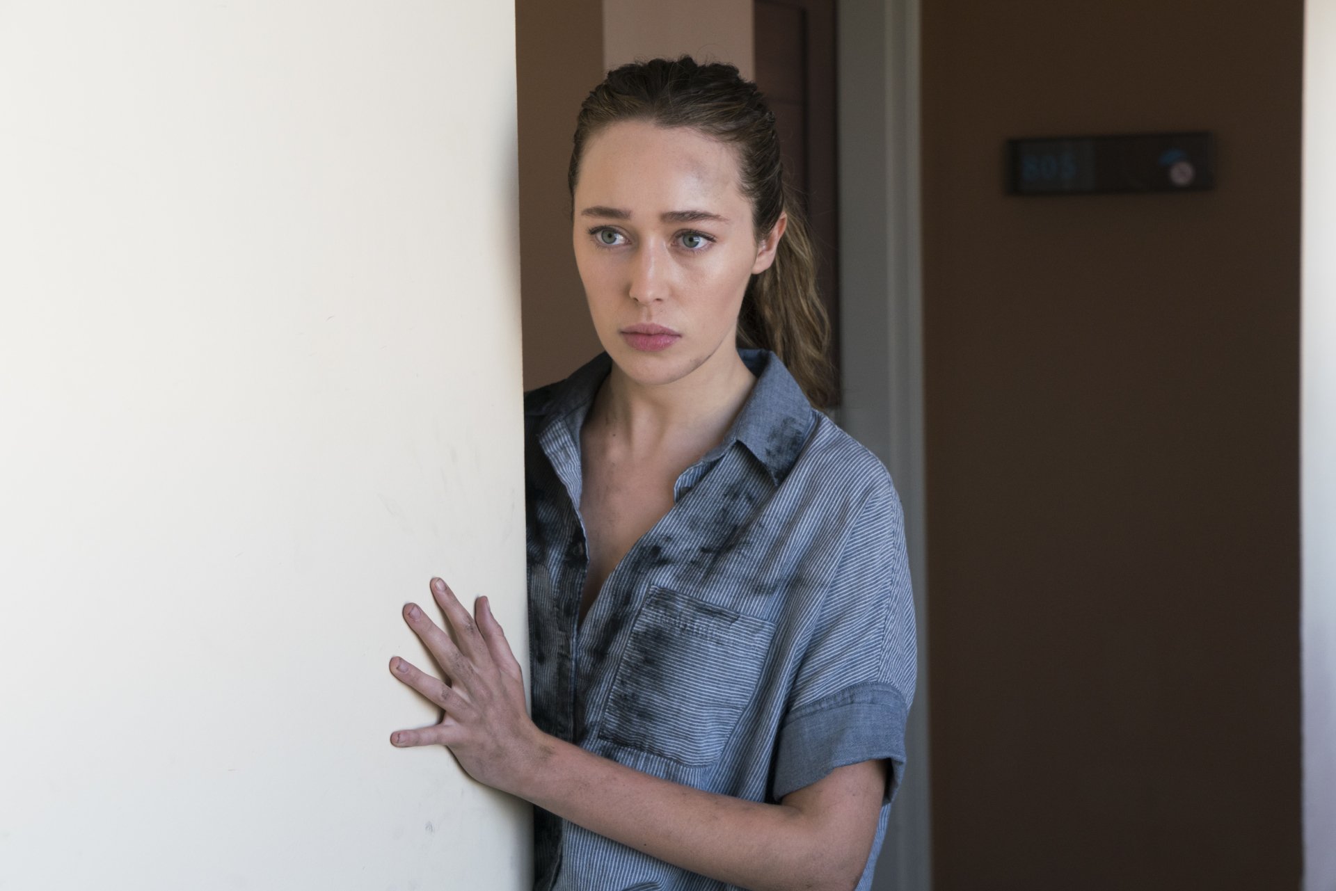 Alicia Clark, portrayed by Alycia Debnam Carey in Fear the Walking Dead, stands cautiously in a doorway in this 4K Ultra HD TV show wallpaper.