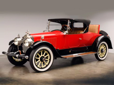 HD desktop wallpaper showing a red 1920 Packard Twin Six Runabout vintage convertible with black soft top, wood-accent interior and whitewall tires on a neutral studio background.