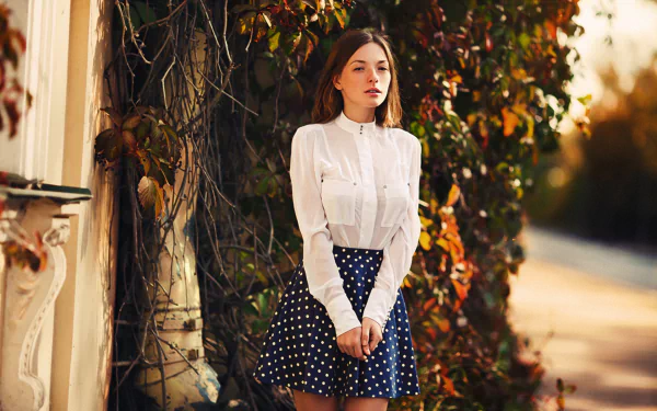Olga Kobzar, a brunette model, stands outdoors wearing a white blouse and polka dot skirt, framed by autumn foliage in this HD PC desktop wallpaper and background.