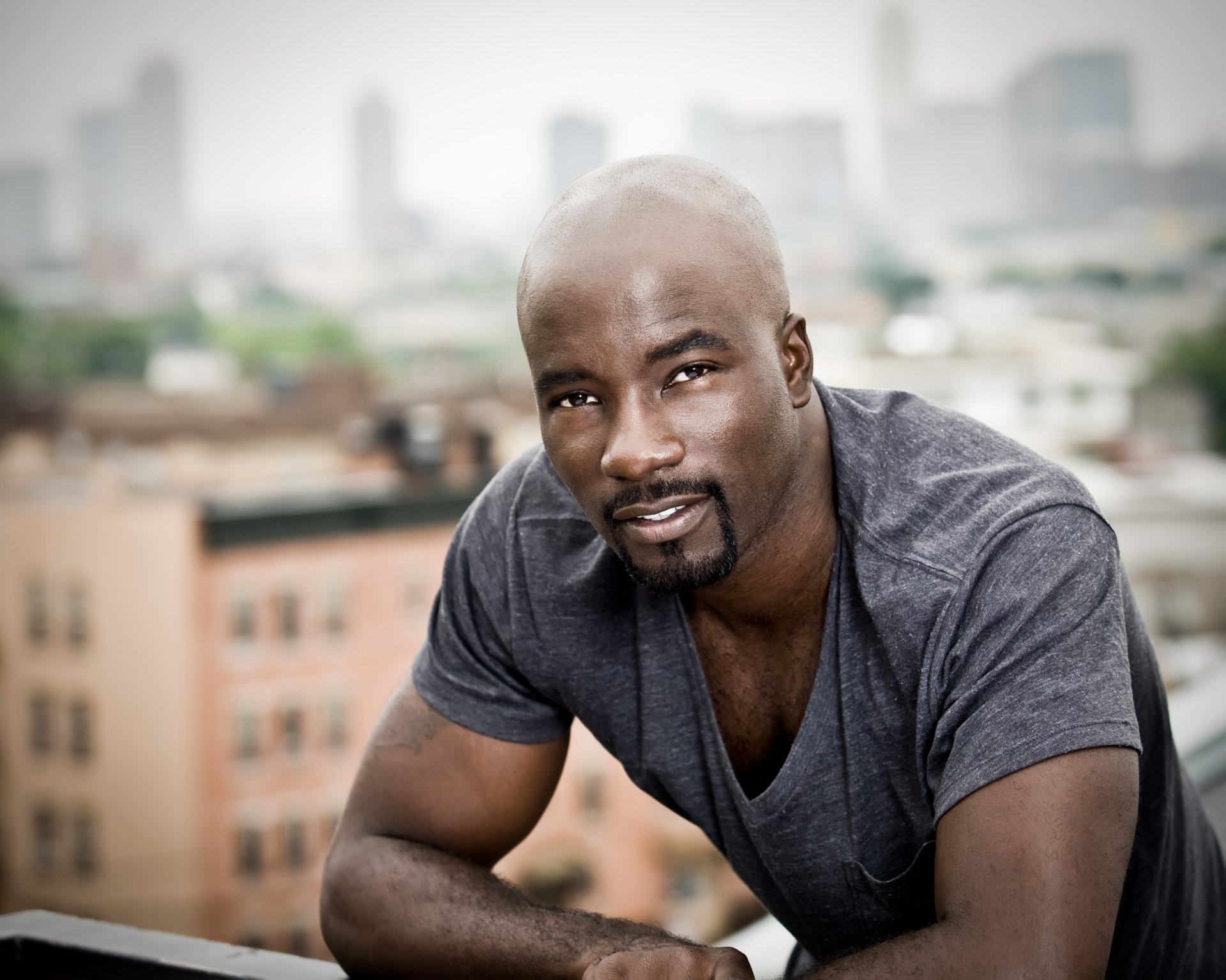HD wallpaper featuring a portrait of Mike Colter with an urban backdrop.