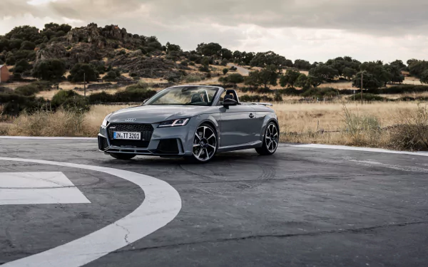 Silver Audi TT convertible on a circular asphalt pad with scrubby hills behind — 4K Ultra HD PC desktop wallpaper showcasing the sleek Audi vehicle.