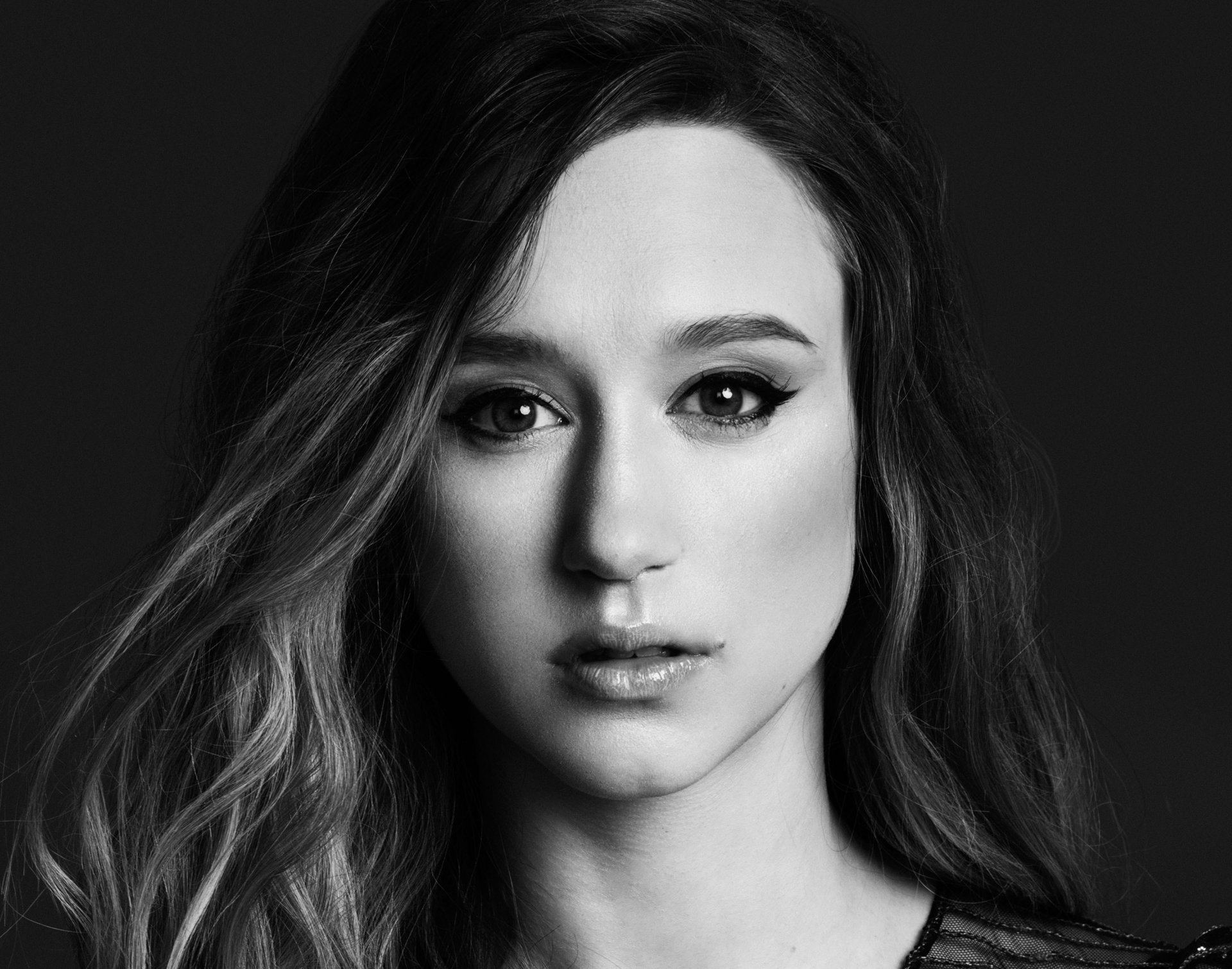 Black and white HD portrait of American actress Taissa Farmiga, showcasing her face with a focused, intense expression on a dark background.