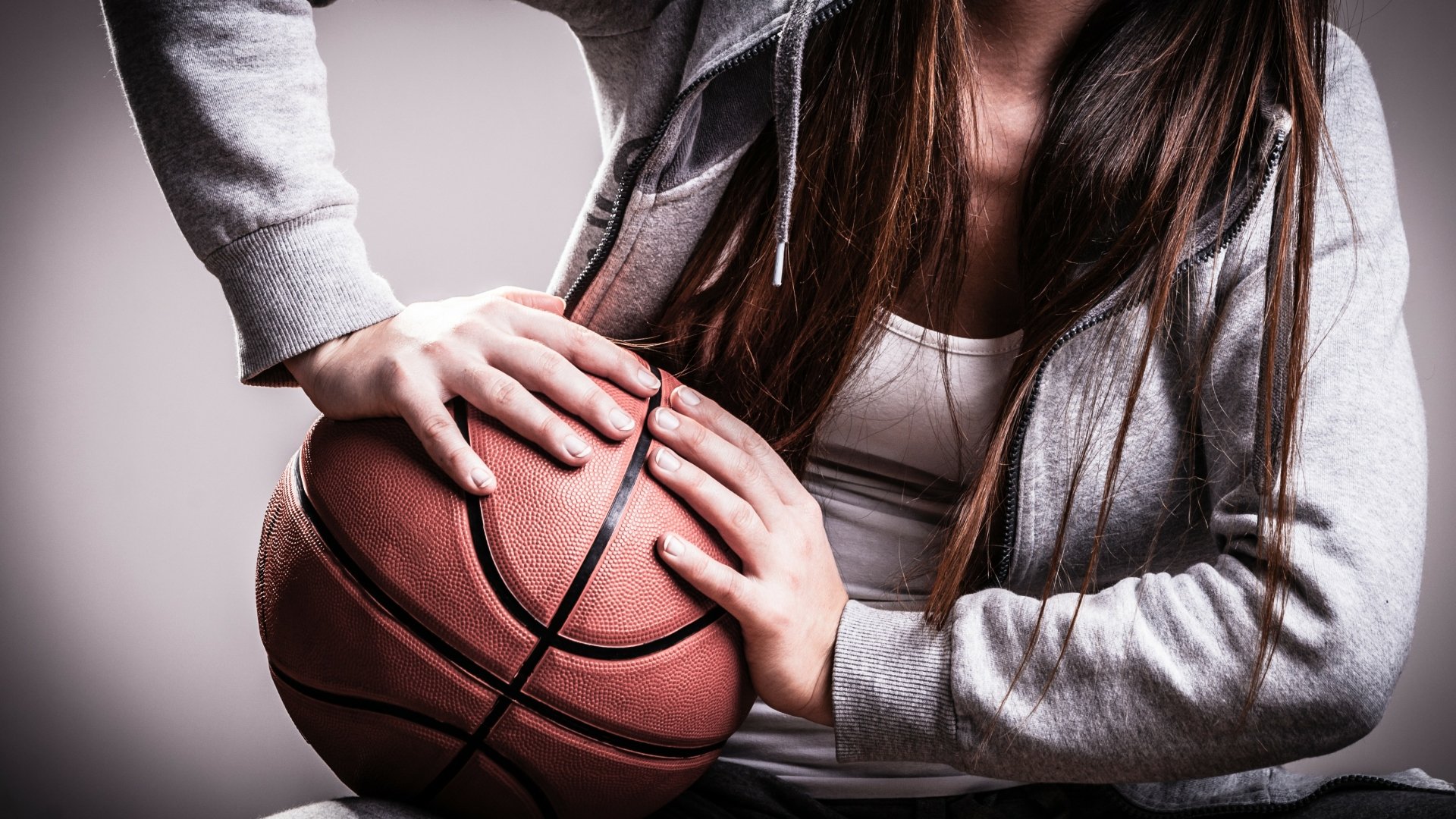 Brunette model gripping a basketball, showcasing the spirit of sports. A dynamic HD background that captures the essence of athleticism and determination.