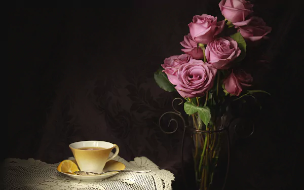Still life photography of pink roses in a glass vase beside a cream teacup and lemon on a lace doily — 4K Ultra HD PC desktop wallpaper and background.