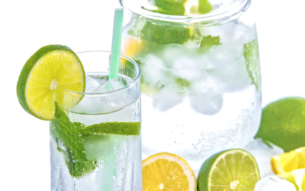 A refreshing glass and pitcher of ice-cold water infused with lime and mint, captured in crisp 4K Ultra HD as a vibrant PC desktop wallpaper.