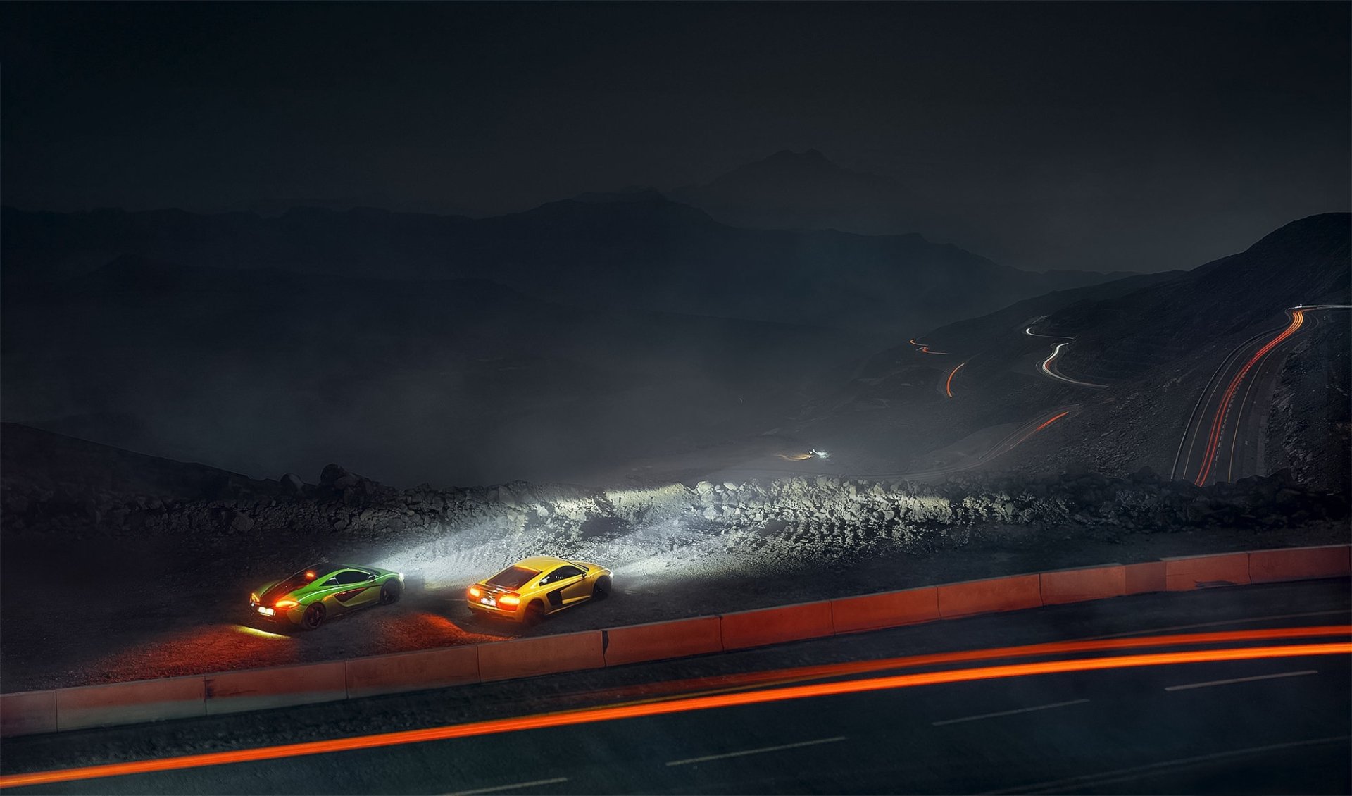 A striking night scene features a yellow McLaren 570S and a green supercar, illuminated against a dark landscape with trails of light from passing vehicles.