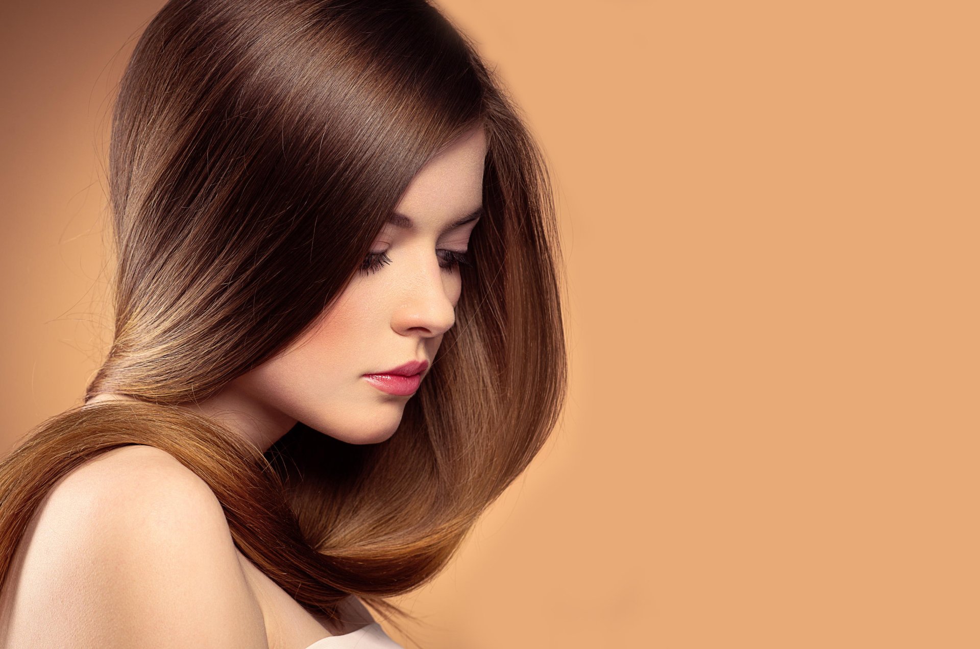 HD desktop wallpaper featuring a brunette woman with sleek hair, portraying a serene mood against a soft, solid background.