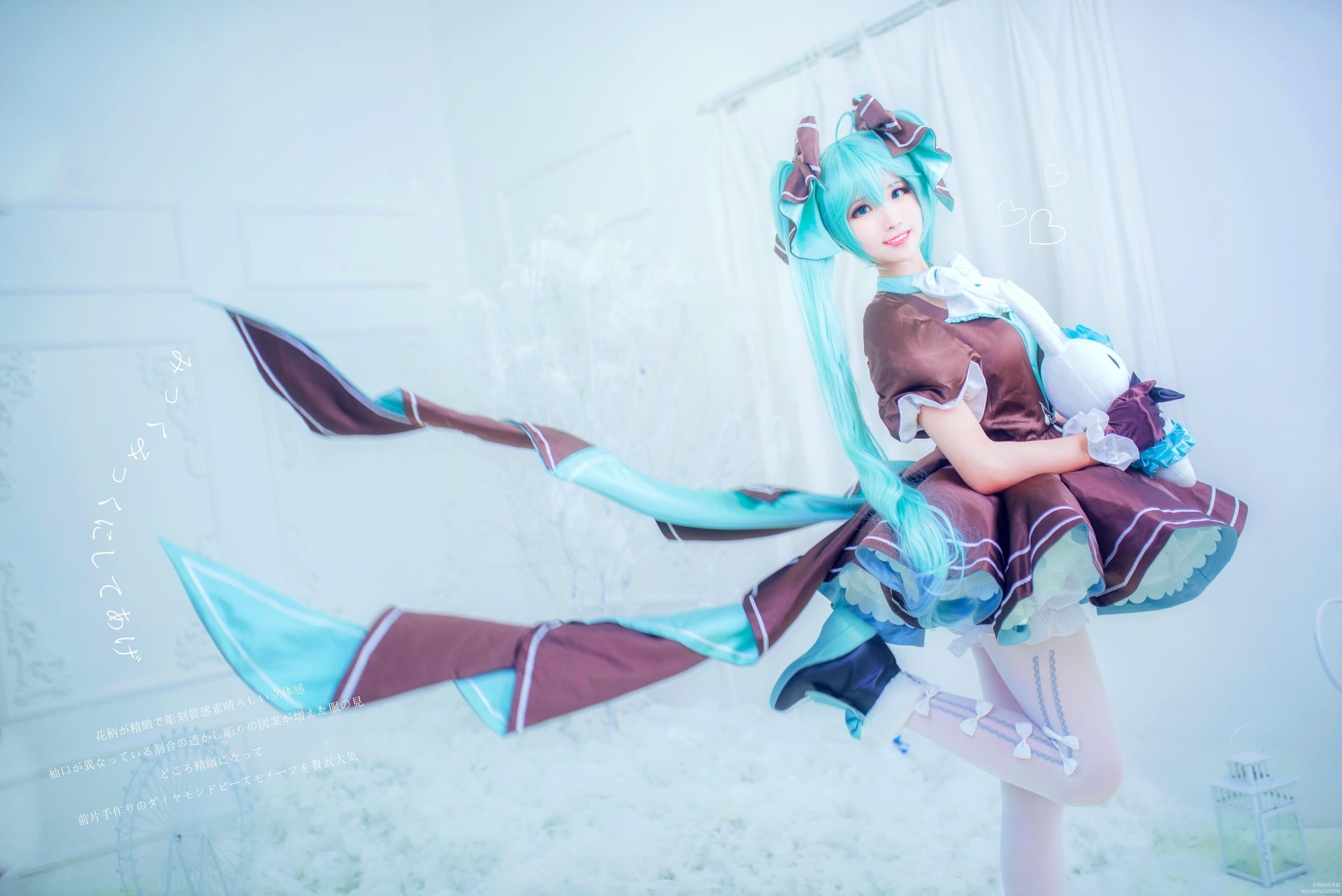 A woman cosplaying as Hatsune Miku, featuring long blue hair and striking blue eyes, poses gracefully with flowing ribbons. A vibrant 4K Ultra HD desktop wallpaper.