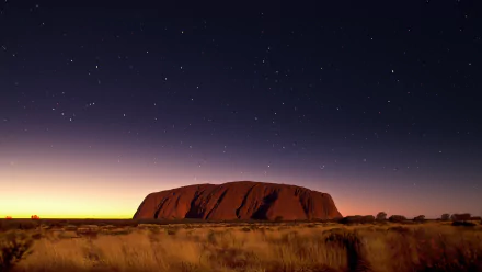 A stunning 4K Ultra HD night landscape of Uluru (Ayers Rock) in the Australian desert beneath a clear, starry sky.