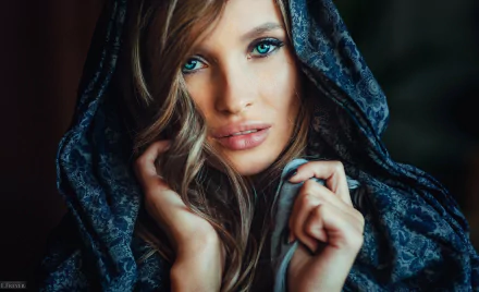Close-up of a brunette model with blue eyes wrapped in a dark patterned hood, featured as an HD PC desktop wallpaper and background.