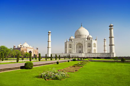 HD desktop wallpaper featuring the iconic Taj Mahal in India, depicting its majestic dome and minarets, surrounded by lush gardens in a serene park setting under a clear blue sky.