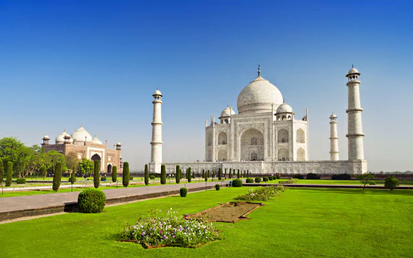 HD desktop wallpaper featuring the iconic Taj Mahal in India, depicting its majestic dome and minarets, surrounded by lush gardens in a serene park setting under a clear blue sky.