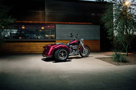 Red Harley-Davidson Freewheeler trike vehicle parked at night by a modern building, moody lighting — HD PC desktop wallpaper/background with crisp, cinematic detail.