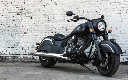 Matte-black Indian Chief Dark Horse motorcycle parked against a weathered white brick wall — HD PC desktop wallpaper and background.