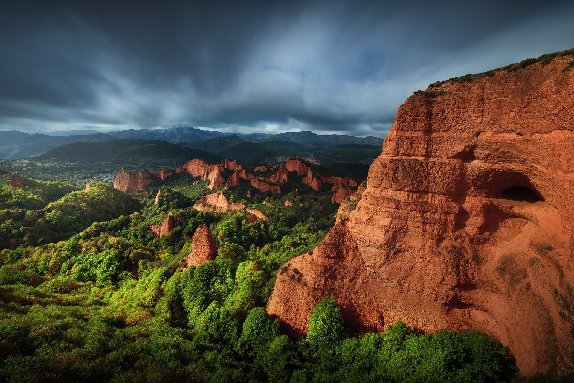 Panoramic HD desktop wallpaper showcasing dramatic cliffs and lush greenery under a moody sky, highlighting the stunning natural landscape.