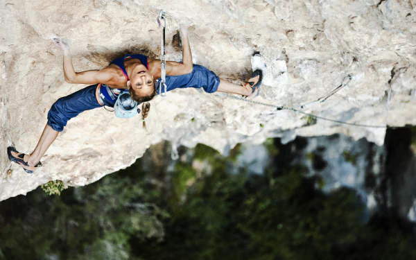 A climber scales a rocky surface, showcasing skill and focus. The image employs depth of field to emphasize the dynamic action of the sport against a vibrant natural backdrop.