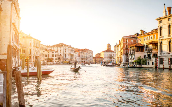 Sunlit Venice canal scene with gondolas gliding past historic Italian buildings, captured in a vibrant HD desktop wallpaper showcasing the city's charming waterways.
