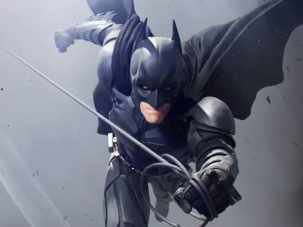 HD PC desktop wallpaper featuring Batman in action from the movie The Dark Knight Rises, showcasing dynamic motion and detailed armor design against a muted background.