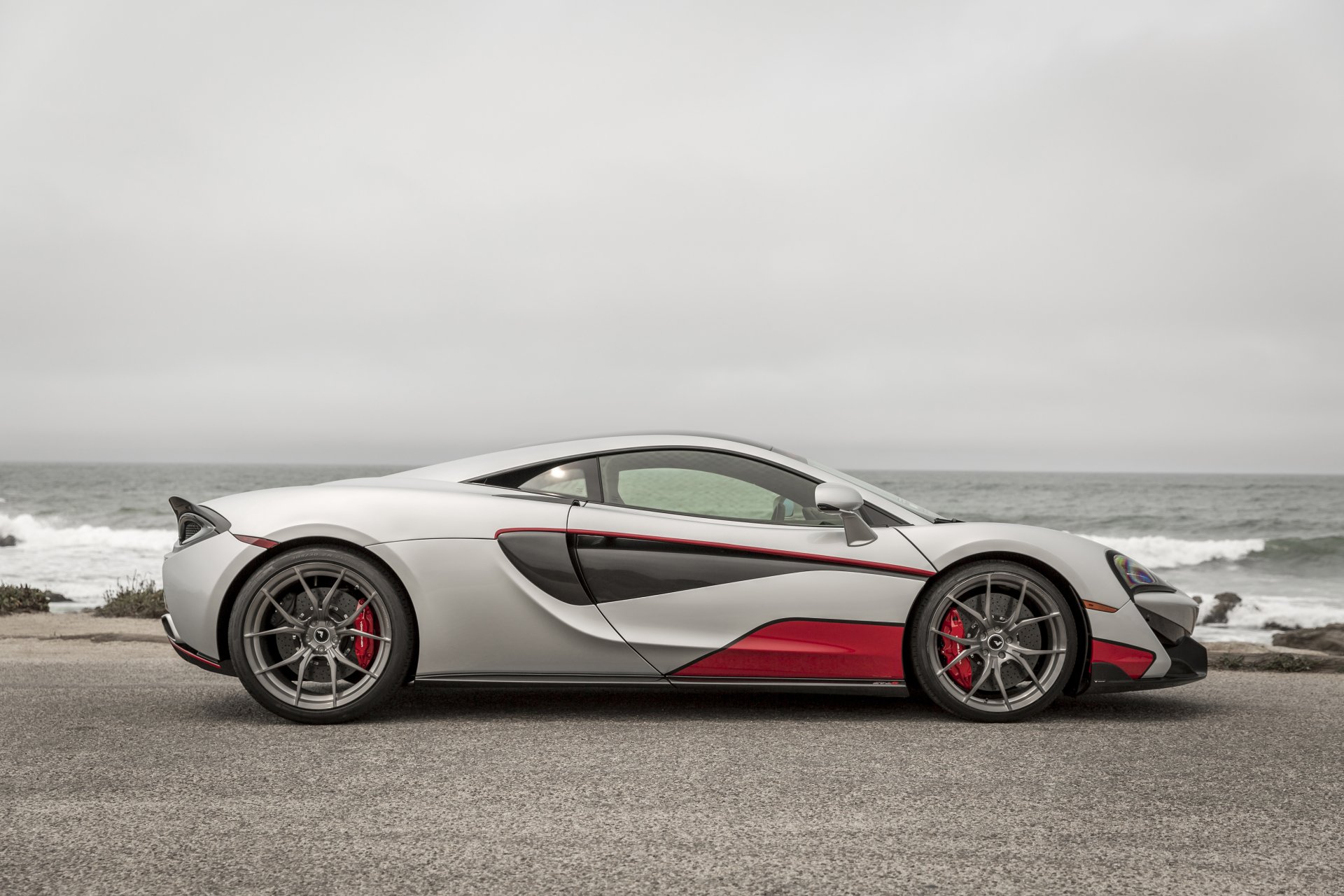 Side profile of a silver Vorsteiner McLaren 570-VX (McLaren 570S) with red accents — a tuning supercar on a coastal road, 4K Ultra HD PC desktop wallpaper.