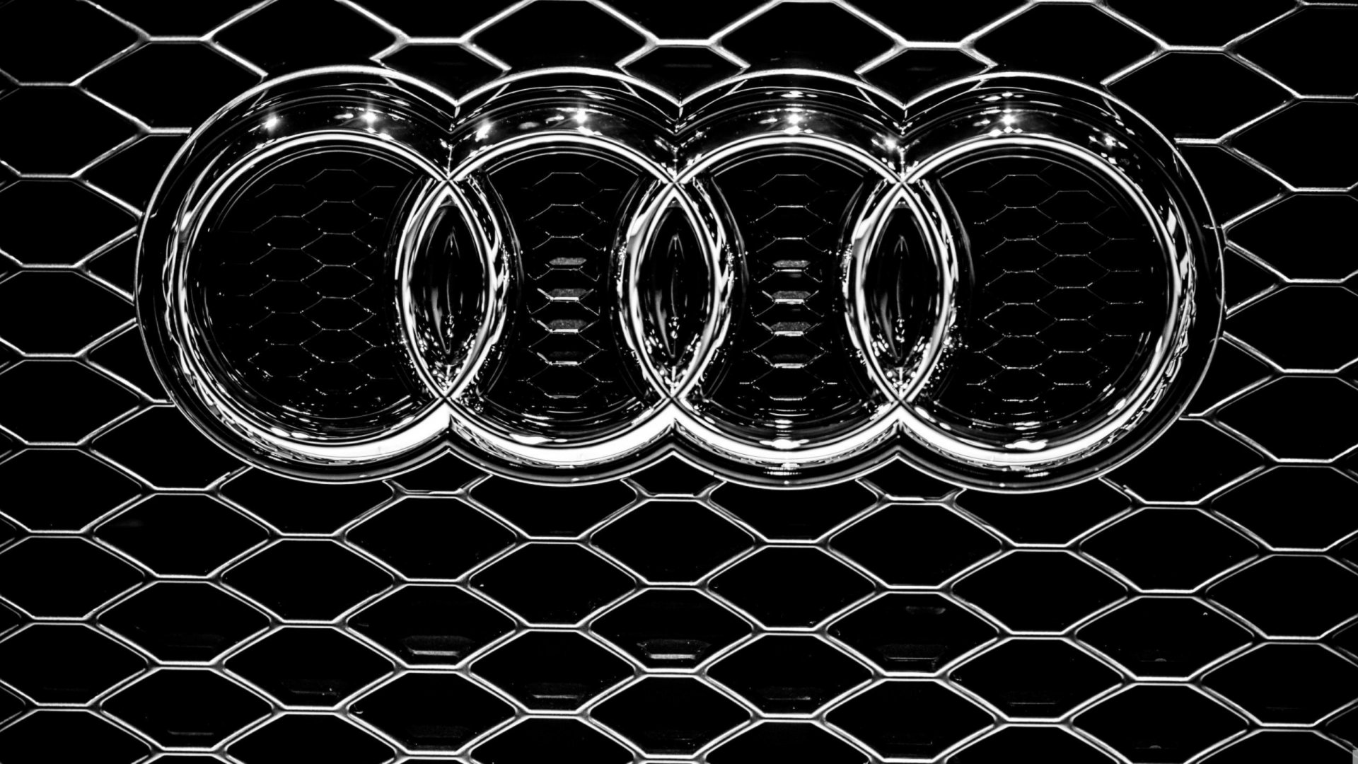 HD desktop wallpaper featuring the Audi logo with a black hexagonal pattern background.