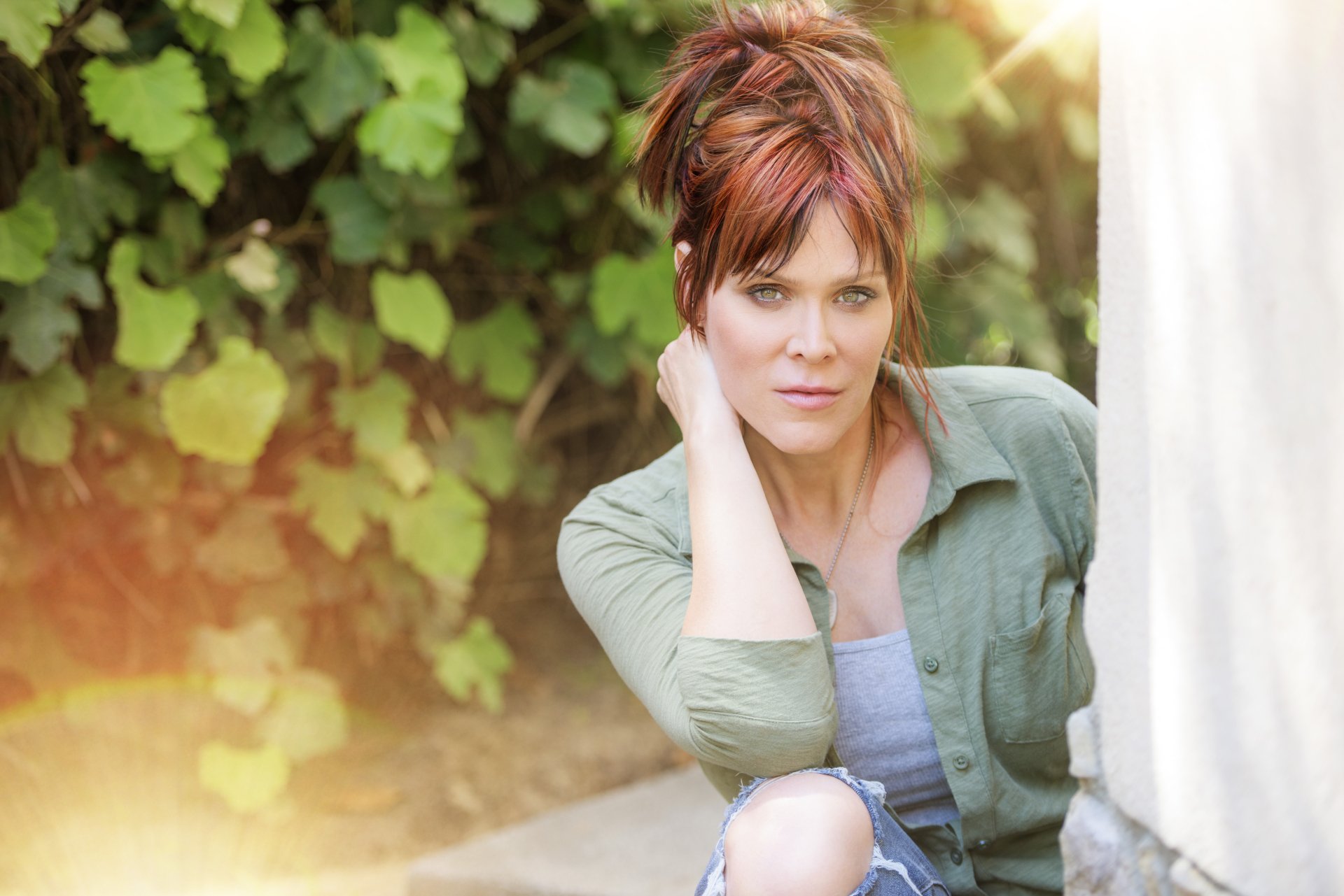 Beth Hart poses outdoors in soft sunlight, captured in a vibrant 4K Ultra HD music-themed PC desktop wallpaper featuring lush greenery in the background.