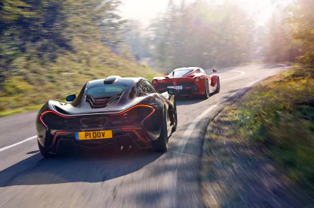 A stunning HD desktop wallpaper featuring a black McLaren P1 and a Ferrari LaFerrari racing on a scenic, winding road. The sunlit backdrop enhances the sleek design and dynamic presence of these supercars.