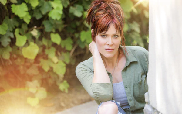 Beth Hart poses outdoors in soft sunlight, captured in a vibrant 4K Ultra HD music-themed PC desktop wallpaper featuring lush greenery in the background.