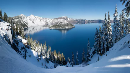 Snow-covered trees frame a clear blue Crater Lake surrounded by snowy mountains in Oregon, captured in crisp 4K Ultra HD quality.