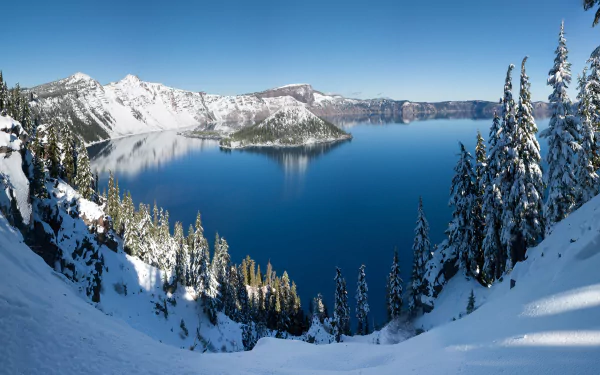 Snow-covered trees frame a clear blue Crater Lake surrounded by snowy mountains in Oregon, captured in crisp 4K Ultra HD quality.