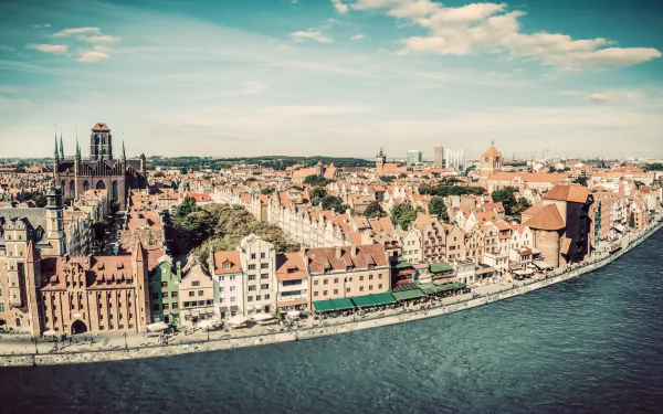 4K Ultra HD PC desktop wallpaper: panoramic Gdańsk, Poland riverside city — historic houses and man-made waterfront along the river under a bright sky.